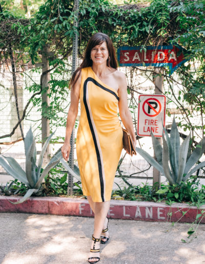 woman in yellow dress in front of parking sign dressed to go out