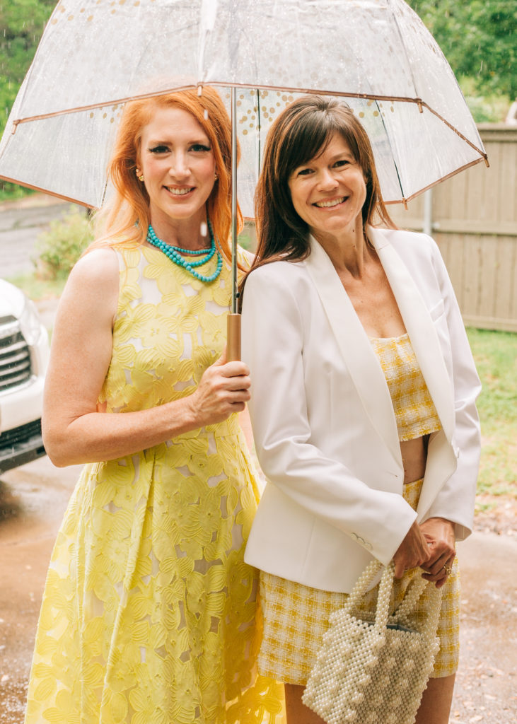 rain umbrella yellow dress white blazer two women standing